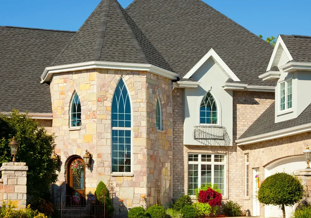 Elegant stone house with tall arched windows and a steep roof.